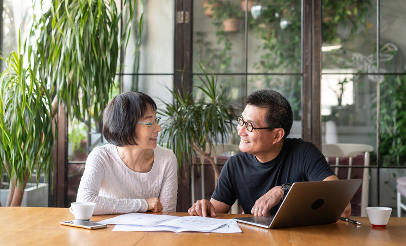 older couple smiling and looking at each other in front of computer